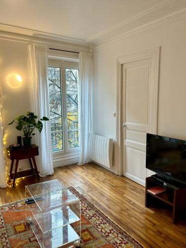un salon avec une table en verre et une télévision dans l'établissement Cosy appartement Montmartre, à Paris