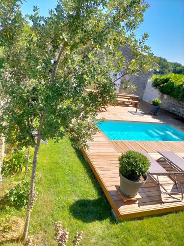 une terrasse en bois avec une piscine dans une cour dans l'établissement Maison familiale de charme 11 personnes dans le Médoc, à Saint-Germain-dʼEsteuil