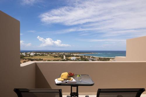 a table on a balcony with a view of the ocean at Panorama Suites in Kastraki Naxou