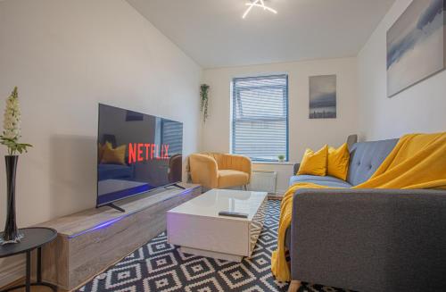 uma sala de estar com um sofá e uma televisão em Beautiful Flat in Halifax - Perfect for Long Stays em Halifax