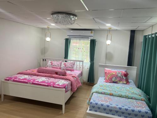 two beds in a room with green curtains at Pani House Hatyai 4 in Hat Yai