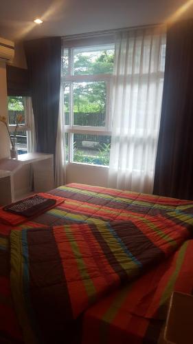 Un dormitorio con una cama colorida y una ventana en A101 The Ocean Pearl, en Pattaya South