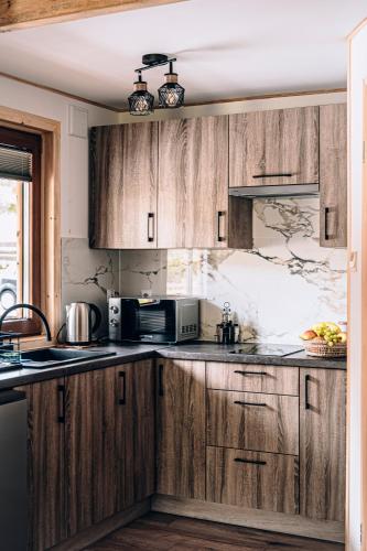 a kitchen with wooden cabinets and a microwave at Górskie Chatki Krysi i Piotrka Bursztynowy in Stronie Śląskie