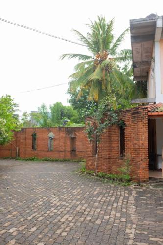 een bakstenen gebouw met een palmboom erachter bij Dulmini Holiday Resort in Anuradhapura