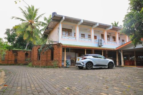 een witte auto geparkeerd voor een gebouw bij Dulmini Holiday Resort in Anuradhapura