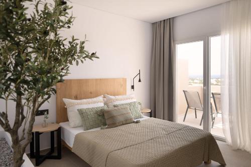 a bedroom with a bed and a table with a plant at Panorama Suites in Kastraki Naxou