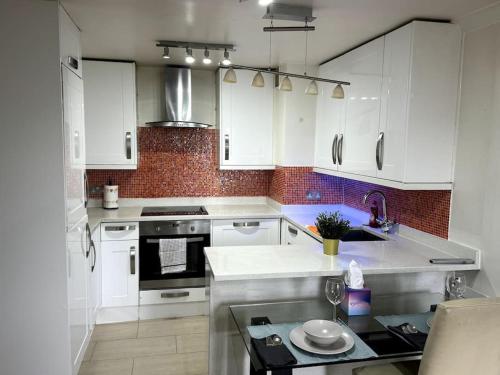 cocina con armarios blancos y fogones en Amazing Earls Court 2 bed Flat with Balcony, en Londres