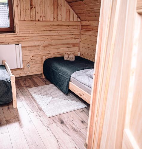 a small room with a bed in a wooden cabin at Górskie Chatki Krysi i Piotrka Bursztynowy in Stronie Śląskie