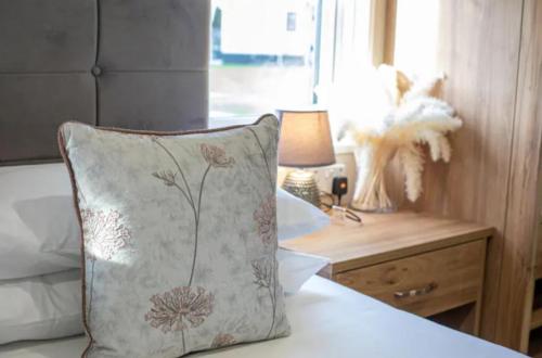 a pillow on a bed next to a table with a lamp at Beautiful 3-Bed Lodge in St Andrews in St. Andrews