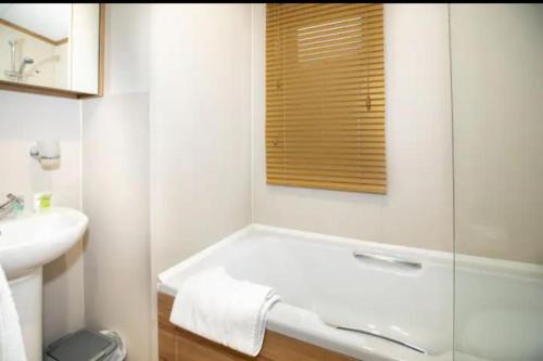 Baño blanco con bañera y lavamanos en Beautiful 3-Bed Lodge in St Andrews, en St Andrews
