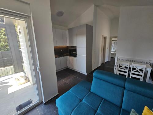 a living room with a blue couch and a kitchen at Seaside Cottage Barbariga in Peroj