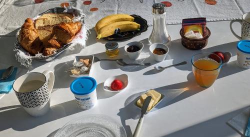 une table avec du pain, des fruits et des boissons dessus dans l'établissement Alix au pays des Pierres Dorées, à Alix
