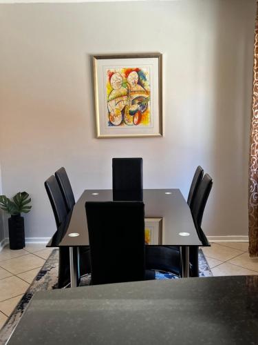 a dining room table with chairs and a painting on the wall at Kimberly Luxury Suites in Kimberley