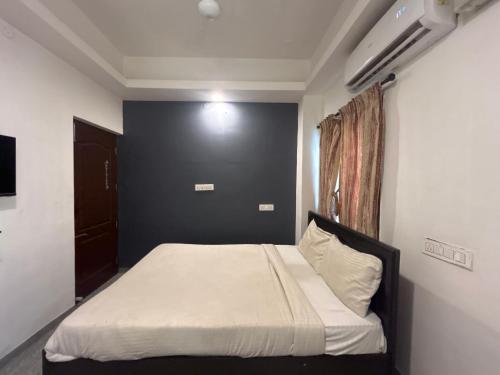 1 dormitorio con 1 cama con pared negra en HOTEL BLUESTONE, en Coimbatore