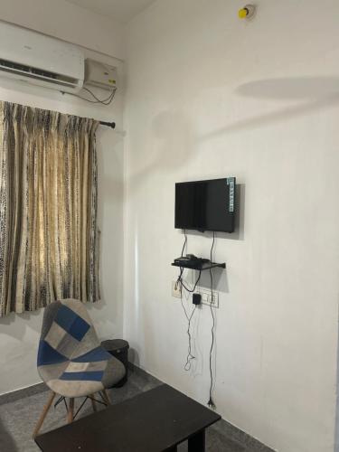 a room with a chair and a television on a wall at HOTEL BLUESTONE in Coimbatore