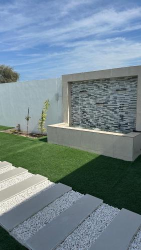 a house with a stone wall and a grass yard at Palma Villa in Mussanah
