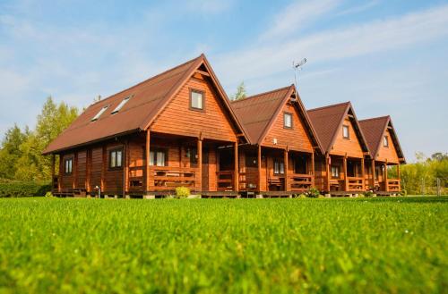 a row of wooden houses in a field of grass at Domki u Jacola Gąski in Gąski