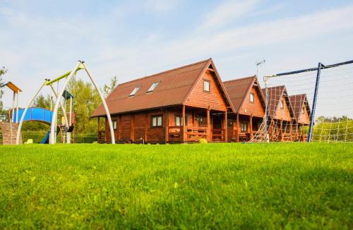 a wooden house with a playground in a field at Domki u Jacola Gąski in Gąski