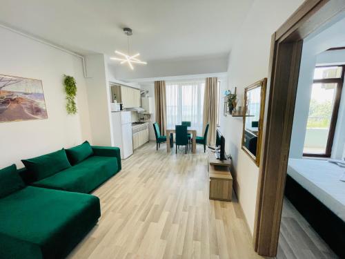 a living room with a green couch and a kitchen at Summerland Studios Nuba in Mamaia