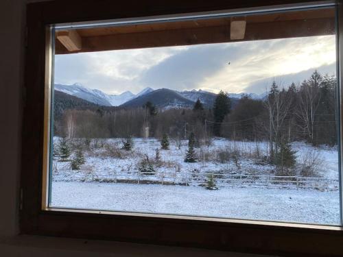 a window view of a snowy field with mountains at La poale de munte in Vistisoara