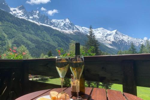 two glasses of wine and bread on a table with mountains at Hôtel Le Labrador in Chamonix-Mont-Blanc