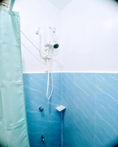 a bathroom with a shower with a blue tiled wall at Charming Duplex Apartment in Tagbilaran City