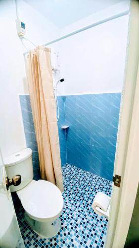 a bathroom with a toilet and a blue tiled floor at Charming Duplex Apartment in Tagbilaran City