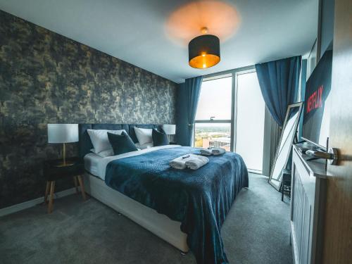 ein Schlafzimmer mit einem Bett mit einer blauen Decke und einem Fenster in der Unterkunft The Safari Suite Luxury Apartment Milton Keynes in Milton Keynes