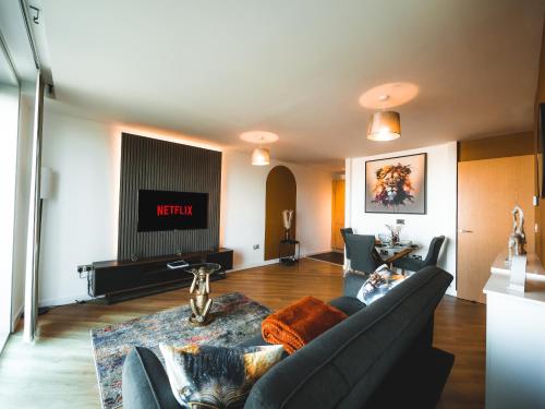 a living room with a couch and a tv at The Safari Suite Luxury Apartment Milton Keynes in Milton Keynes