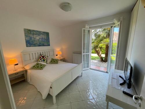a bedroom with a white bed and a sliding glass door at Villa I Giardini del Conero con ombrellone in spiaggia in Porto Recanati