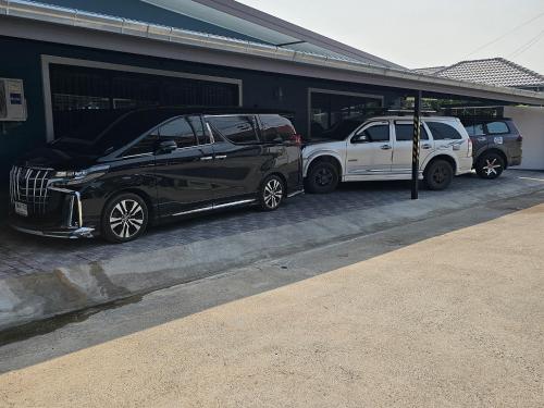 dos autos estacionados en un estacionamiento al lado de un edificio en Pool Villa Baan Sanook Cha-am, en Cha Am