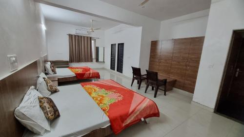 a bedroom with two beds and a table and chairs at Hotel Mayur Inn in Udaipur