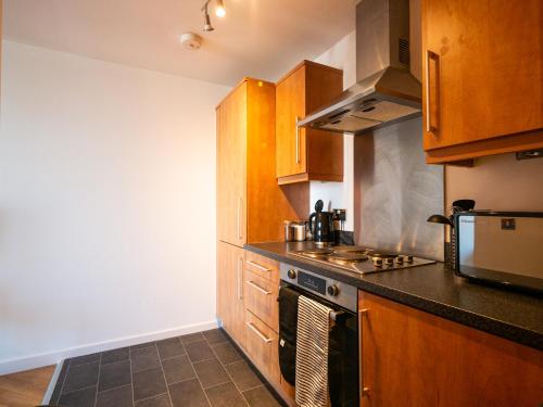 a kitchen with wooden cabinets and a stove top oven at The Safari Suite Luxury Apartment Milton Keynes in Milton Keynes