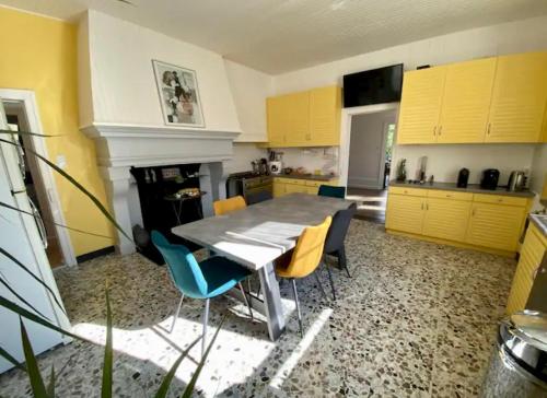une cuisine avec des armoires jaunes, une table et des chaises dans l'établissement Chambre privée dans spacieuse maison de maître, à Cousancelles