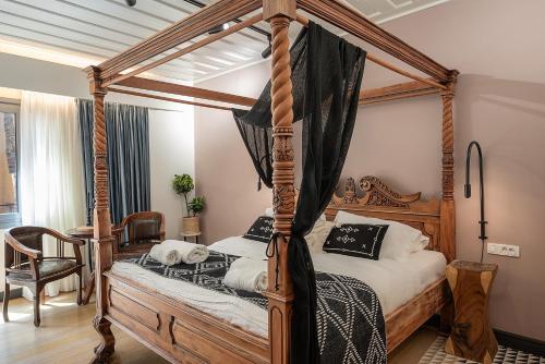 Vranas Ambiance Hotel في مدينة خانيا: غرفة نوم مع سرير بأربعة أعمدة