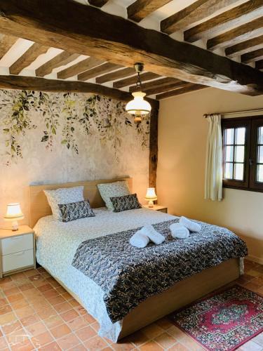 une chambre avec un lit avec deux oreillers dessus dans l'établissement Chaumière à l'étang des anémones, à Sainte-Hélène-Bondeville