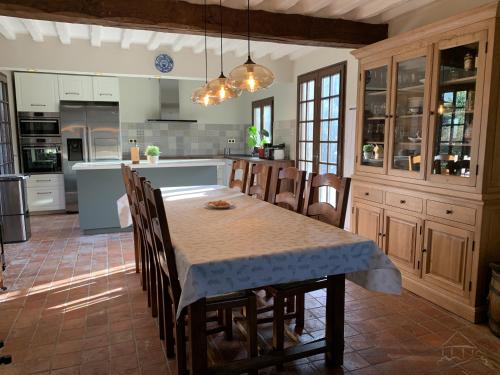 une cuisine avec une table et des chaises dans une pièce dans l'établissement Chaumière à l'étang des anémones, à Sainte-Hélène-Bondeville