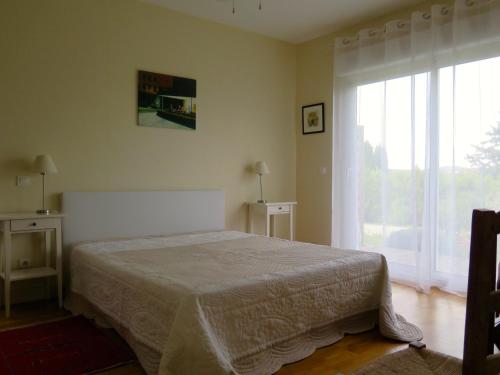 um quarto com uma cama e uma grande janela em Gîte de l'Olympe em Aspiran