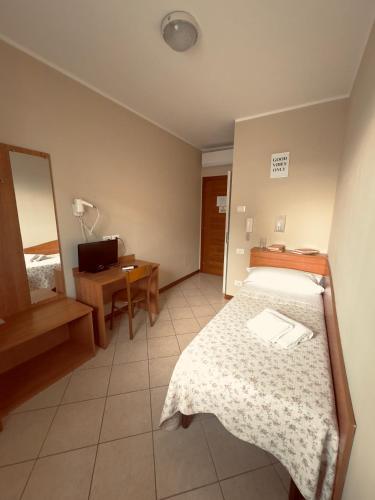 a bedroom with a bed and a desk and a mirror at Albergo Trattoria AL TAJ in Sevegliano