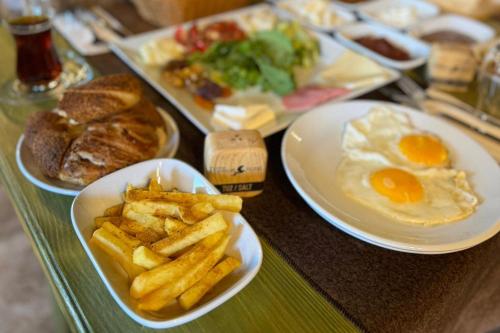 a table topped with plates of food with eggs and french fries at Uçhisar Premium in Nevsehir
