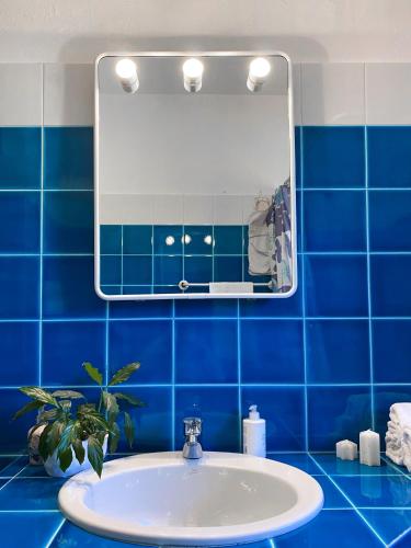 a blue tiled bathroom with a sink and a mirror at Casa ridente in Arzachena