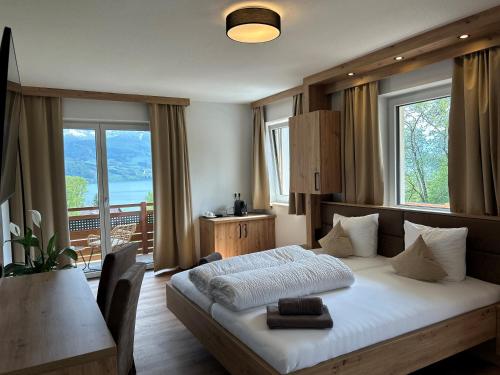a bedroom with a bed and a table and windows at Gasthof Steinbichler in Nussdorf am Attersee