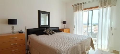 a bedroom with a bed with a mirror and a window at Royal Cabanas Golf by Amandio Batista in Cabanas de Tavira