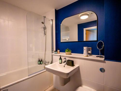 uma casa de banho com um lavatório branco e um espelho. em The Safari Suite Luxury Apartment Milton Keynes em Milton Keynes