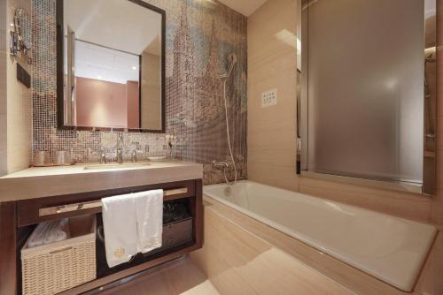 a bathroom with a tub and a sink and a mirror at WISDOM Boutique Hotel in Beijing