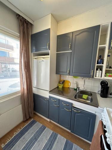 uma cozinha com armários azuis, um lavatório e uma janela em Studio apartment near the center em Jyväskylä