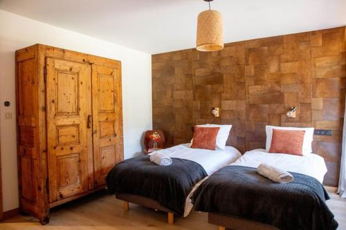 a bedroom with two beds and a wooden wall at Chalet Holtanna in Montriond
