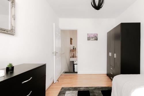 a bedroom with white walls and a black dresser at 4 Bed House - Sleeps 6 - Garden Pets Wifi in London