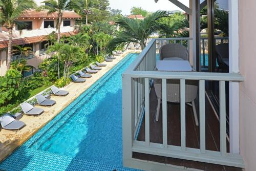 d'un balcon avec vue sur la piscine et ses chaises longues. dans l'établissement Anantasila Beach Resort Hua Hin, à Hua Hin