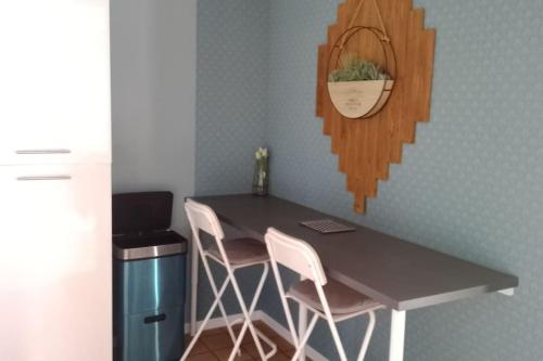 une cuisine avec une table et deux chaises blanches dans l'établissement Gîte à la campagne avec étang de pêche, à Amplier